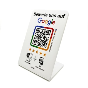 Könnte beinhalten: Weißer Kunststoffständer mit Google-Logo, QR-Code und dem Text "Bewerte uns auf Google". Der Ständer hat außerdem fünf goldene Sterne und Anweisungen zum Scannen des Codes mit einem Telefon.
