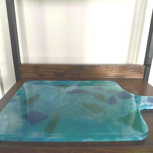 Charcuterie board made from resin.  Blue green and clear glass tile embeds