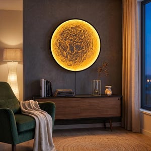 May include: A circular wall-mounted lamp featuring a detailed, textured lunar surface illuminated with a warm, golden glow. The light is encased in a thin black frame and emits a soft radiance, highlighting the craters and topography of the moon.