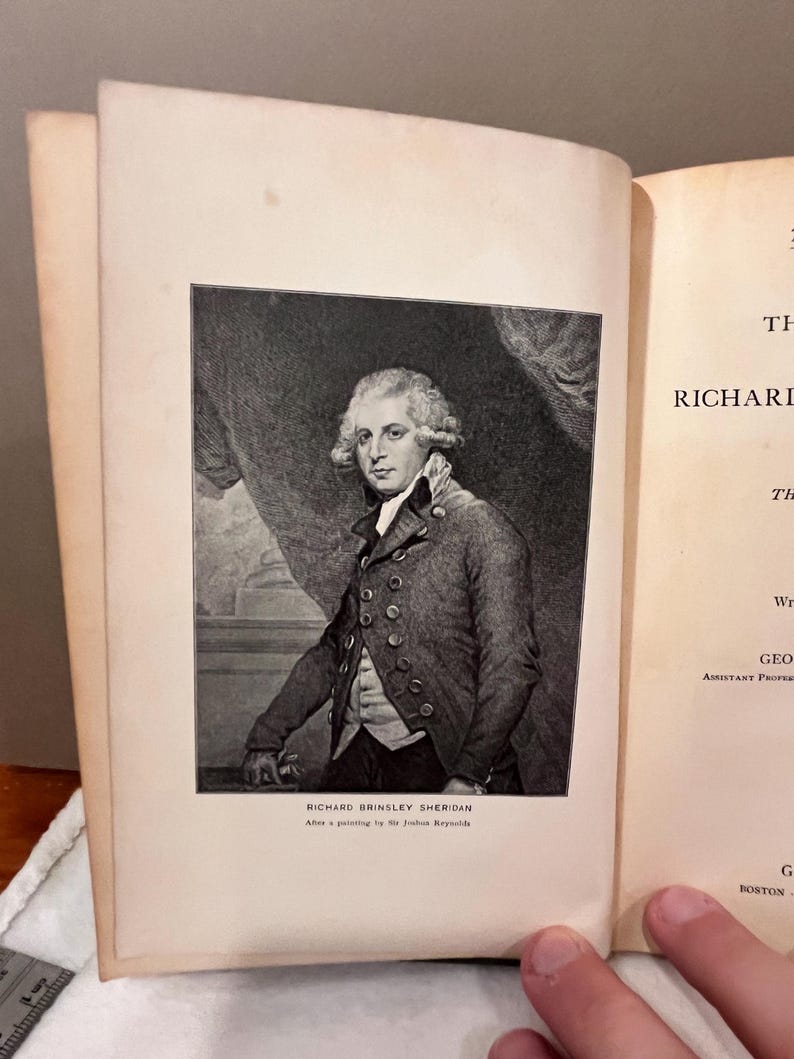 May include: An open book featuring a black and white portrait of Richard Brinsley Sheridan. The portrait is a detailed engraving, with the text "RICHARD BRINSLEY SHERIDAN" and "After a painting by Sir Joshua Reynolds" below the image.