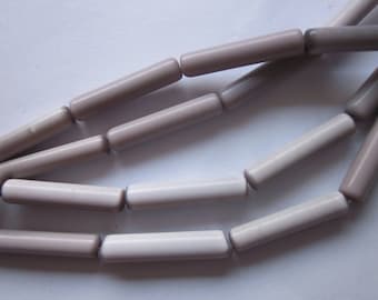 Può includere: Una collana di perline in ceramica di colore grigio chiaro e bianco. Le perline sono cilindriche e hanno una finitura liscia e opaca.