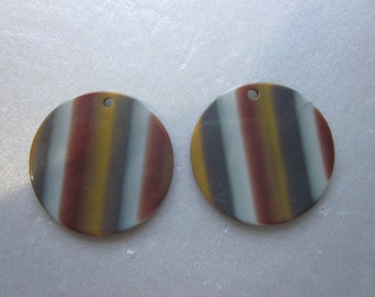 May include: Two round, striped, iridescent, decorative ornaments with a hole in the center. The stripes are in shades of gray, white, brown, and yellow.