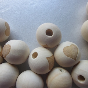 May include: A collection of wooden beads with a heart design. The beads are natural in color and have a smooth, polished finish.