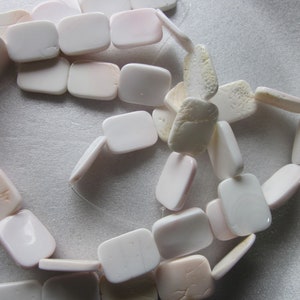 May include: A strand of white and off-white rectangular shell beads. The beads are smooth and have a natural, organic look.