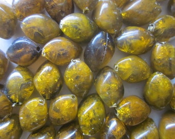 May include: A collection of translucent, amber-colored, oval-shaped beads with a sparkly, iridescent finish. The beads are approximately 1 inch in length.