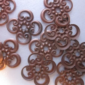 Pode incluir: Um grupo de enfeites metálicos de cor cobre com um design floral decorativo. Os enfeites são intrincados e têm uma aparência delicada, semelhante a um filigrana.