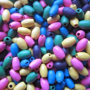 May include: A large assortment of wooden oval beads in various colours, including pink, blue, yellow, green, and purple.