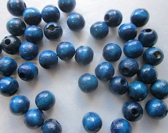 May include: A collection of blue wooden beads with a smooth, slightly textured finish. The beads are round and have a hole through the center for stringing.