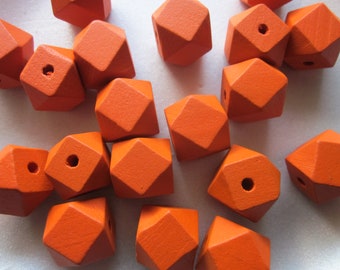 Può includere: Una collezione di perline di legno arancione con forme geometriche sfaccettate. Ogni perlina ha un foro, suggerendo che siano per essere infilate. Le perline sono di un vibrante colore arancione pieno.