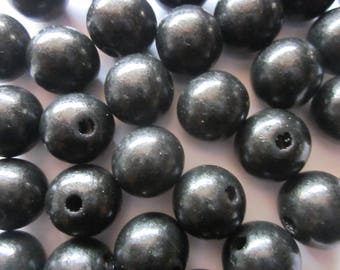 May include: A close-up of a group of black wooden beads. The beads are round and have a smooth, glossy finish. They are all the same size and have a small hole drilled through the center.