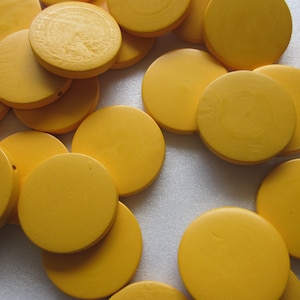 May include: A group of round, yellow wooden beads. The beads are smooth and have a glossy finish.