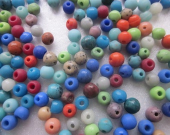 May include: A large assortment of colorful glass beads in various shades of blue, green, red, orange, brown, and white. The beads are round and have a smooth, glossy finish.