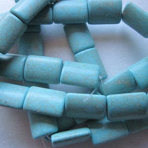 May include: A strand of turquoise blue rectangular beads with a light brown marbling pattern. The beads are strung on a clear thread.