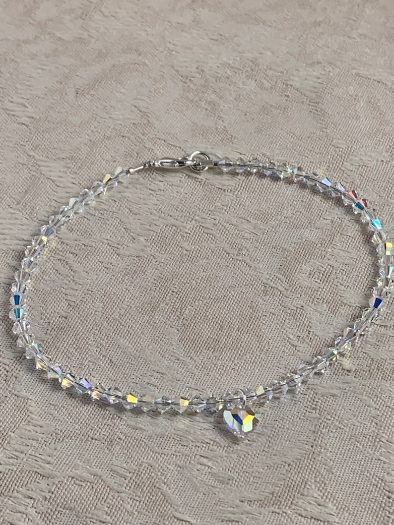 Pu&ograve; includere: Una delicata cavigliera di cristallo trasparente con un ciondolo a forma di cuore. La cavigliera &egrave; composta da piccoli cristalli sfaccettati collegati da una chiusura color argento. Il ciondolo a forma di cuore &egrave; anch'esso realizzato in cristallo trasparente.