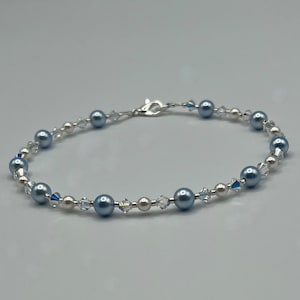 May include: A delicate bracelet featuring alternating blue and white pearls with clear crystal accents.