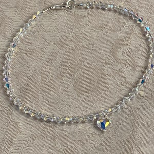 Pu&ograve; includere: Una delicata cavigliera di cristallo trasparente con un piccolo ciondolo a forma di cuore. La cavigliera &egrave; composta da piccoli cristalli sfaccettati infilati con una catena e chiusura color argento. Il ciondolo a forma di cuore riflette pi&ugrave; colori.