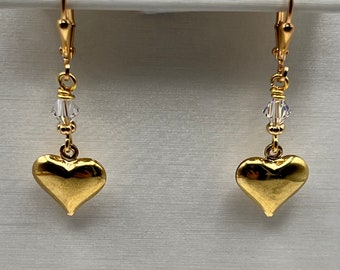 May include: Gold heart dangle earrings with a clear crystal bead on each earring.