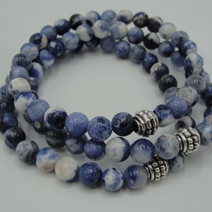 May include: A triple-wrap bracelet made with blue and white patterned beads and silver accents.