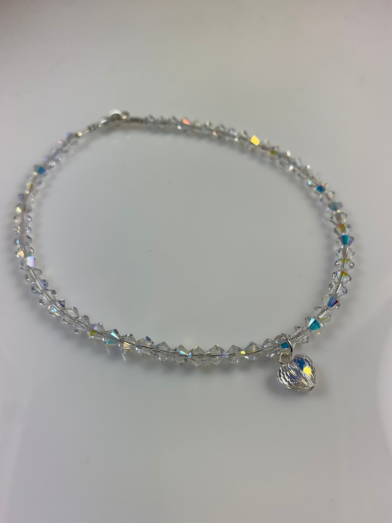 Pu&ograve; includere: Una cavigliera di perline di cristallo trasparente con un piccolo ciondolo a forma di cuore. La cavigliera &egrave; composta da piccoli cristalli sfaccettati infilati su un filo sottile. Il ciondolo a forma di cuore &egrave; anch'esso realizzato in cristallo trasparente.