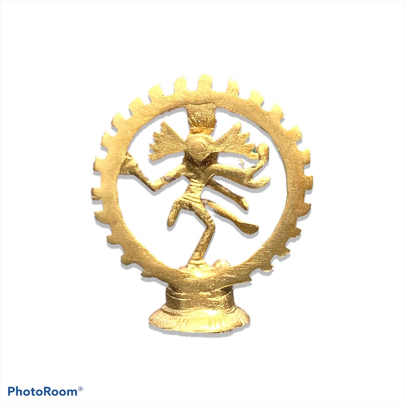 May include: A gold-colored statue of a dancing deity, framed by a circular, gear-like design. The figure has multiple arms and is posed dynamically. The statue is set on a pedestal, and the overall design is intricate and detailed.
