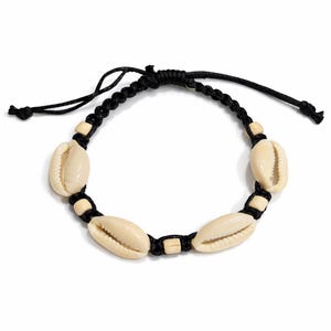 Puede incluir: Una pulsera de macramé negro con seis conchas de cauri de color crema. La pulsera es ajustable con un cierre de nudo corredizo. Las conchas están espaciadas uniformemente a lo largo del cordón negro.