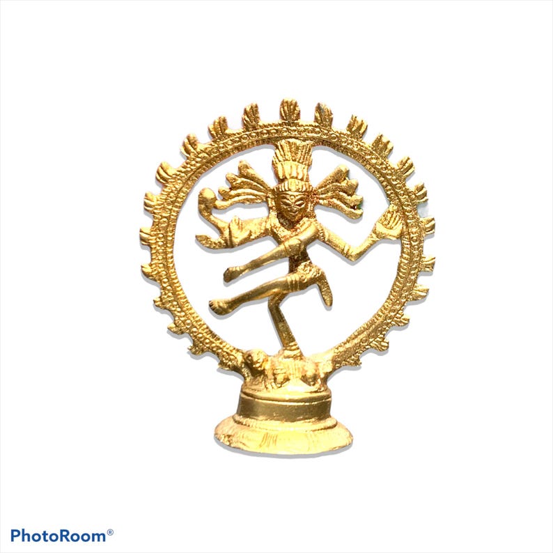 May include: A gold-colored statue of the Hindu deity Shiva Nataraja, the dancing god. The statue depicts Shiva in a dynamic pose within a circular frame, with multiple arms and intricate details. The base is a pedestal.