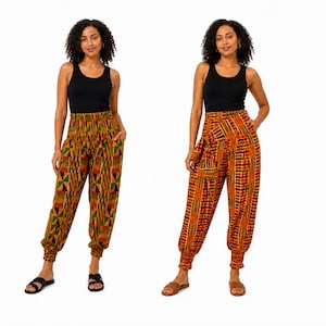 Op de afbeelding: Twee afbeeldingen van een persoon die een zwarte tanktop en een broek met patroon draagt. De broek is oranje, bruin, groen en zwart met een geometrisch ontwerp. Eén paar heeft een riem. De broek heeft zakken en is bij de enkels afgezet.