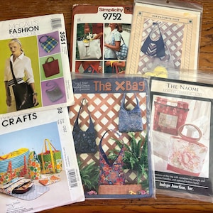 May include: A collection of sewing patterns for various tote bags and accessories. The patterns include designs for handbags, purses, and totes, with images of the finished products. The patterns are from brands like McCall's, Simplicity, and Indygo Junction.