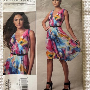May include: An Anne Klein Vogue Patterns American Designer sewing pattern envelope V1223, size FF (16-18-20-22). The envelope features a sleeveless, knee-length wrap dress with a V-neckline and a thin black belt, showcasing a colorful floral print.