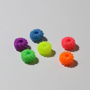 Puede incluir: Un conjunto de pequeñas cuentas redondas en varios colores: morado, azul, verde, amarillo, rosa y naranja. Cada cuenta tiene un diseño en espiral, creando una apariencia texturizada. Adecuadas para la fabricación de joyas y manualidades.