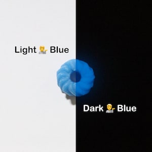 K&ouml;nnte beinhalten: Ein hellblaues, ringf&ouml;rmiges Objekt mit einem Loch in der Mitte, vor einem wei&szlig;en und schwarzen Hintergrund. Der Text "Light Blue" und "Dark Blue" wird angezeigt. Das Objekt scheint zu leuchten.