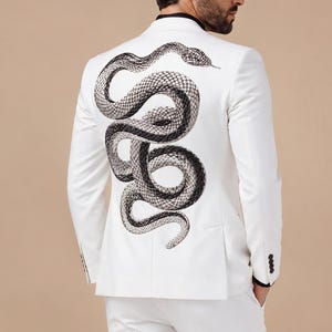 May include: White suit with a detailed snake design on the jacket's back. The snake is depicted in grey and black, contrasting against the white suit. The suit has a tailored fit. The trousers are also white.