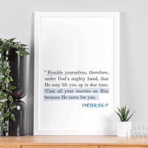 Puede incluir: Un cuadro enmarcado con el texto "Echando toda vuestra ansiedad sobre él, porque él tiene cuidado de vosotros" de 1 Pedro 5:6-7. El texto es azul sobre un fondo blanco. El cuadro se exhibe sobre una superficie de madera con una planta y un jarrón decorativo.