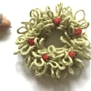 Peut inclure: Une couronne de laine verte décorée de pompons rouges.