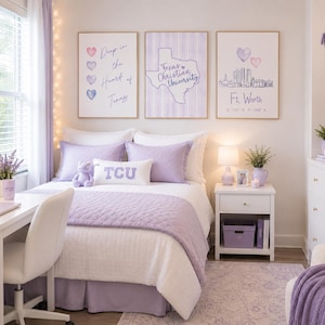 May include: A bedroom decorated in shades of purple, featuring a bed with a lavender quilt and pillows. Artwork with hearts and the Texas Christian University logo hangs above the bed. A white desk and nightstand complete the room's decor.