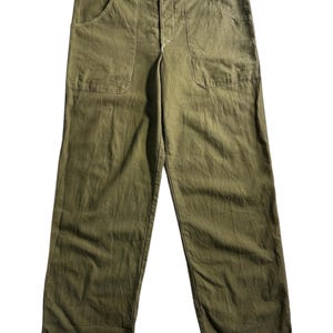 May include: Olive green trousers with two front pockets and white stitching. The trousers have a button fastening and a relaxed fit. The fabric looks like a lightweight cotton or linen blend. Suitable for casual wear, these trousers are a versatile wardrobe staple.