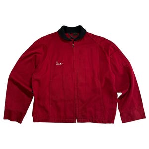 Puede incluir: Chaqueta roja con cuello negro y cierre de cremallera. La palabra "Sea" está bordada en el pecho izquierdo. La chaqueta tiene dos bolsillos delanteros y mangas largas. Hecha de tela suave.