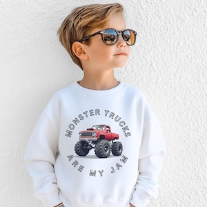 Puede incluir: Sudadera blanca con un gr&aacute;fico de cami&oacute;n monstruo rojo y el texto "Monster Trucks Are My Jam". El dise&ntilde;o incluye una ilustraci&oacute;n detallada de un cami&oacute;n monstruo con neum&aacute;ticos grandes. La sudadera est&aacute; hecha de un material suave.