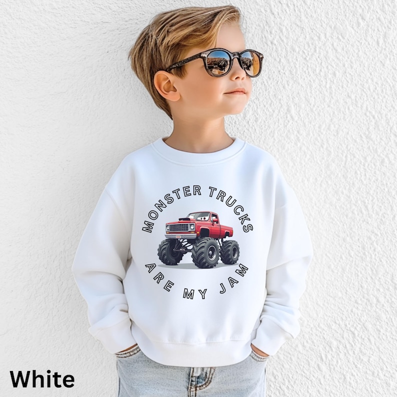 Puede incluir: Sudadera blanca con un gr&aacute;fico de cami&oacute;n monstruo rojo y el texto "Monster Trucks Are My Jam". El dise&ntilde;o incluye una ilustraci&oacute;n detallada de un cami&oacute;n monstruo con neum&aacute;ticos grandes. La sudadera est&aacute; hecha de un material suave.