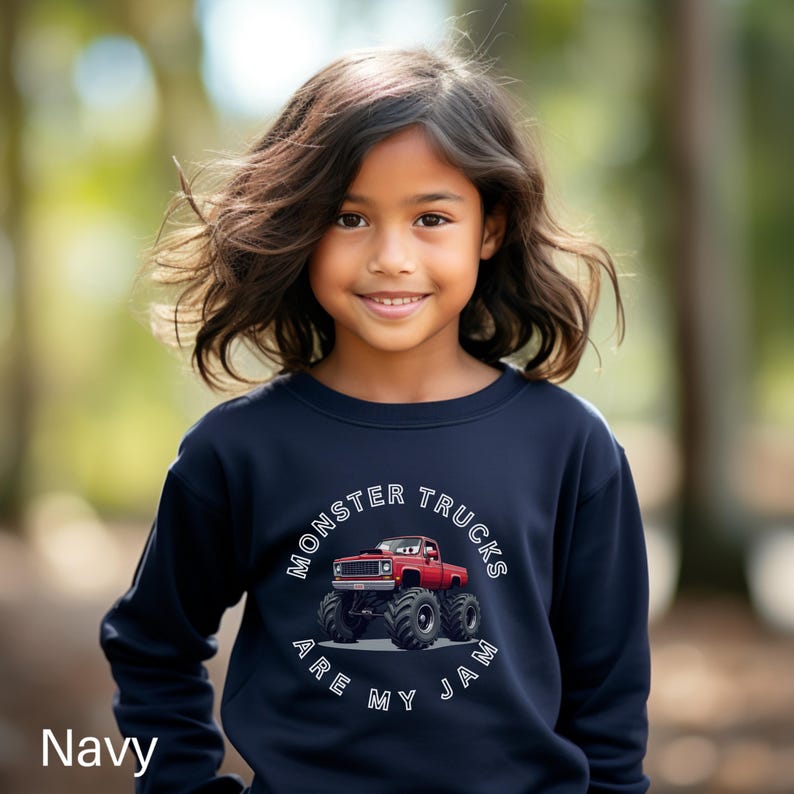 Puede incluir: Sudadera azul marino con un gr&aacute;fico de un cami&oacute;n monstruo rojo y neum&aacute;ticos negros grandes. El texto "MONSTER TRUCKS ARE MY JAM" est&aacute; impreso en un dise&ntilde;o circular blanco. La palabra "Navy" est&aacute; impresa en la parte inferior izquierda.