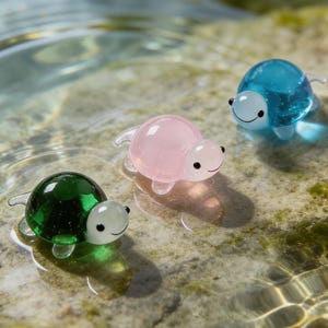 May include: Three glass turtle figurines in green, pink, and blue float in water. Each turtle has a smiling face and clear flippers. The turtles are a decorative item.