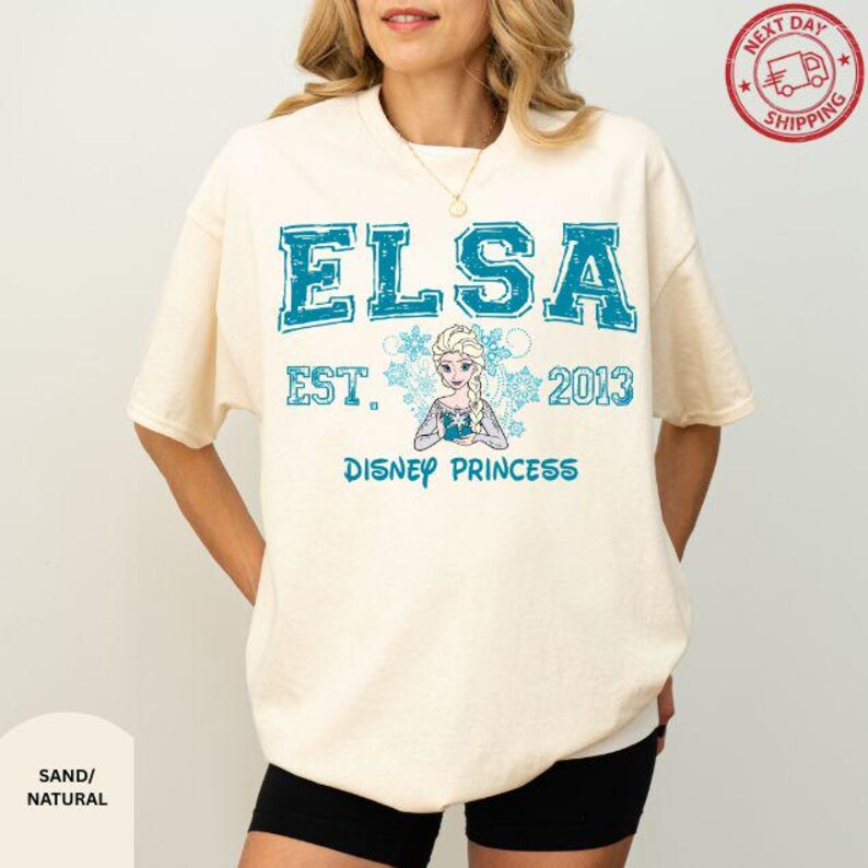 A woman wearing a white t-shirt with a graphic design featuring the character Elsa from the Disney movie Frozen.