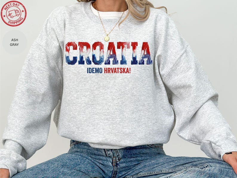 A person wearing a grey sweatshirt with the word "Croatia" printed on it, along with the text "IDEMO HRVATSKA!" printed below.