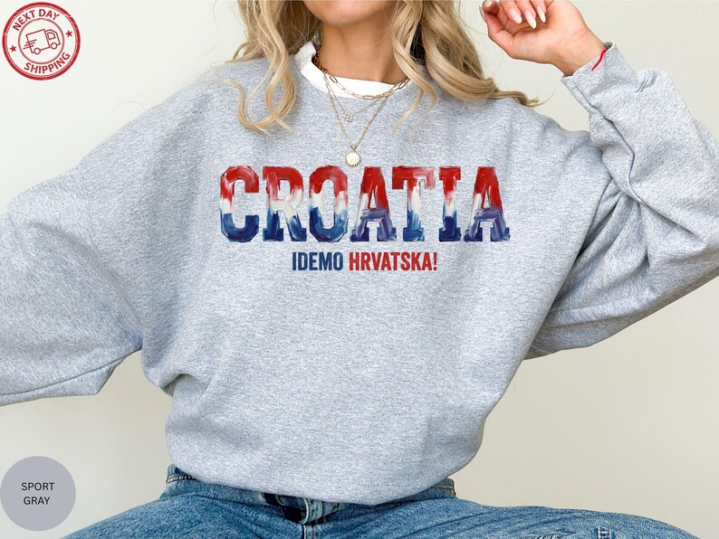A person wearing a grey sweatshirt with the word "Croatia" printed on it, along with the text "IDEMO HVRATSKA!" printed below.