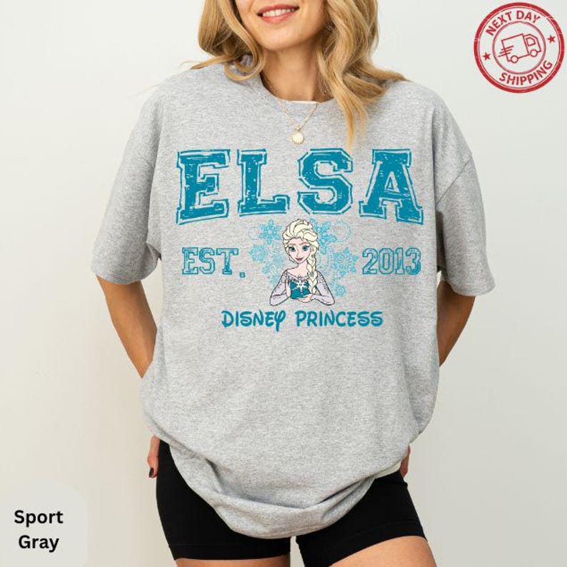 A woman wearing a gray t-shirt with a graphic design featuring the character Elsa from the Disney movie Frozen.