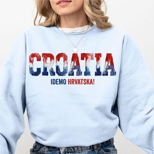 A woman wearing a light blue sweatshirt with the word "Croatia" printed on it.