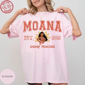 A woman wearing a pink t-shirt with the text "Moana Est. 2016 Disney Princess" printed on it.