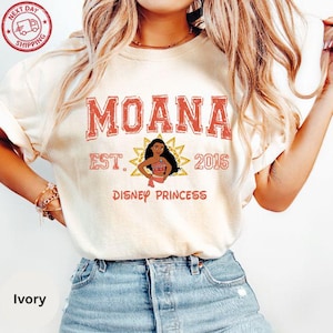 A woman wearing a white t-shirt with the text "Moana Est. 2016 Disney Princess" printed on it, along with a graphic of Moana.