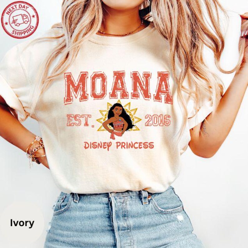 A woman wearing a white t-shirt with the text "Moana Est. 2016 Disney Princess" printed on it, along with a graphic of Moana.