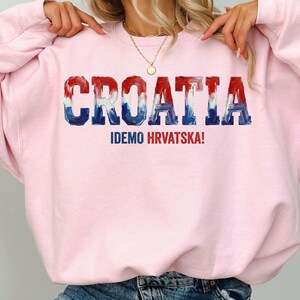 A person wearing a pink sweatshirt with the word "Croatia" printed on it.